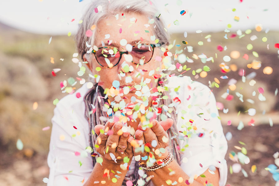Mujer mayor soplando confeti
